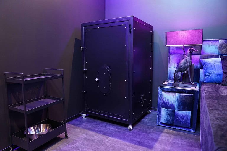 Hochwertiger BDSM Raum mit Safe, Stuhl und Dekoration für außergewöhnliche Erlebnisse.