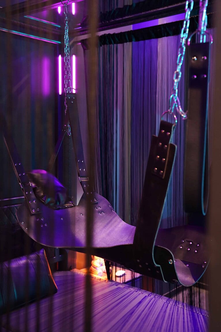 Hochwertiger BDSM-Hotelraum mit Wandseil und Ledersitzen in München.