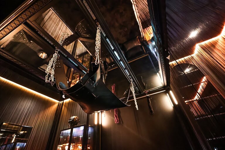 Hintergrund mit bondage Schaukeln und stilvoller Beleuchtung, ideal für BDSM und Fetisch Erlebnisse.