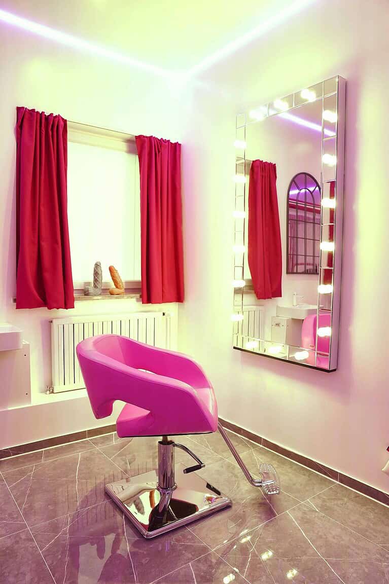 Hübscher Blick auf einen stilvollen BDSM Raum mit pinkem Stuhl und Spiegelbeleuchtung.